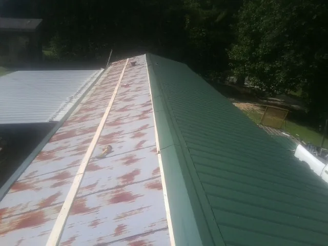 Old rusted panels beside newly installed green metal roofing — Wind Damage Roof Repair by Roofing Brothers in Crownsville