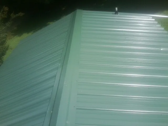 New green metal panels meeting at the ridge of a roof — Flat Roof Repair work by our crew in Crownsville