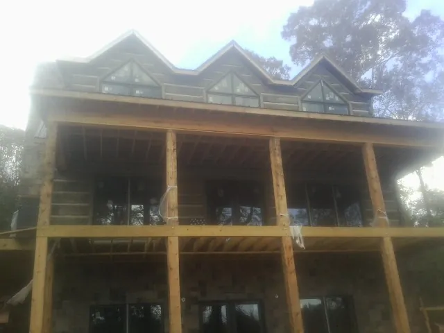 Dormers and porch framing on a large log home under construction — Roof Coating work by our crew in Crownsville