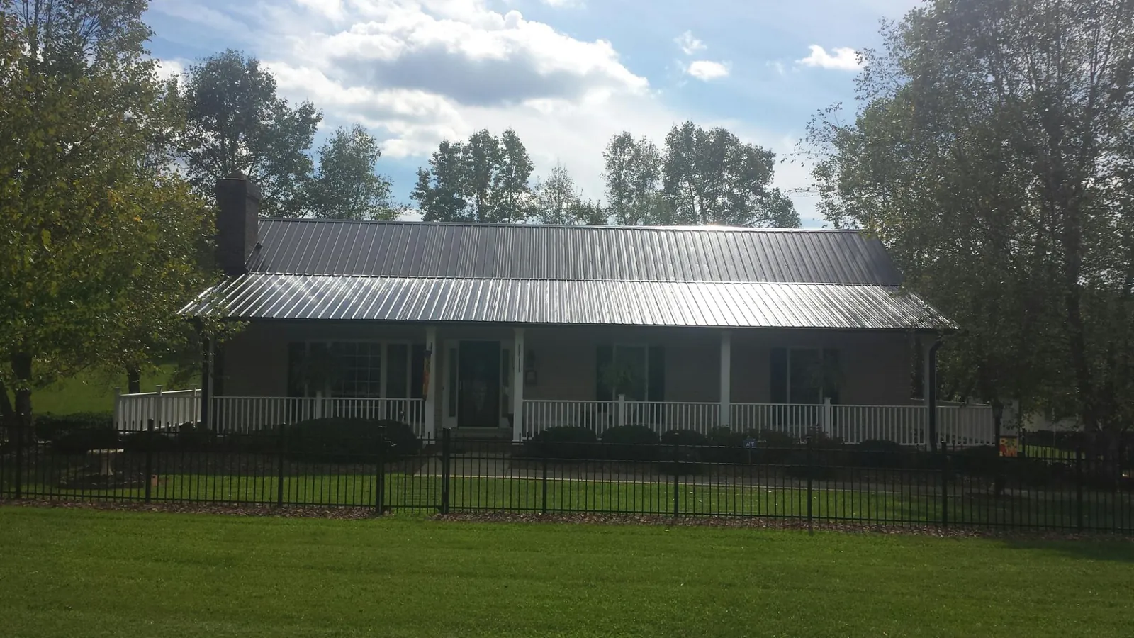 Gray metal roof on a brick ranch with a full width front porch — Gutter Guard Installation work by our crew in Crownsville