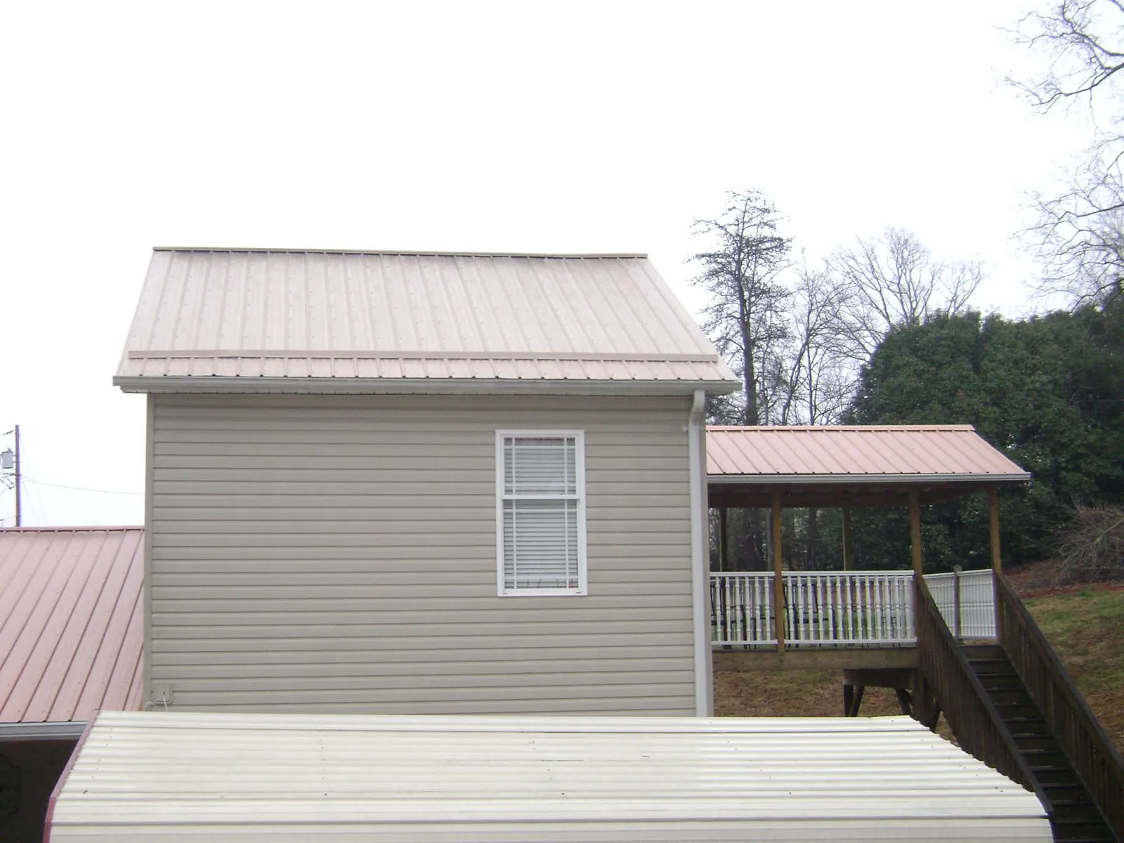 Tan metal roofs on a two story addition and attached porch, from a Roof Replacement job in Crownsville