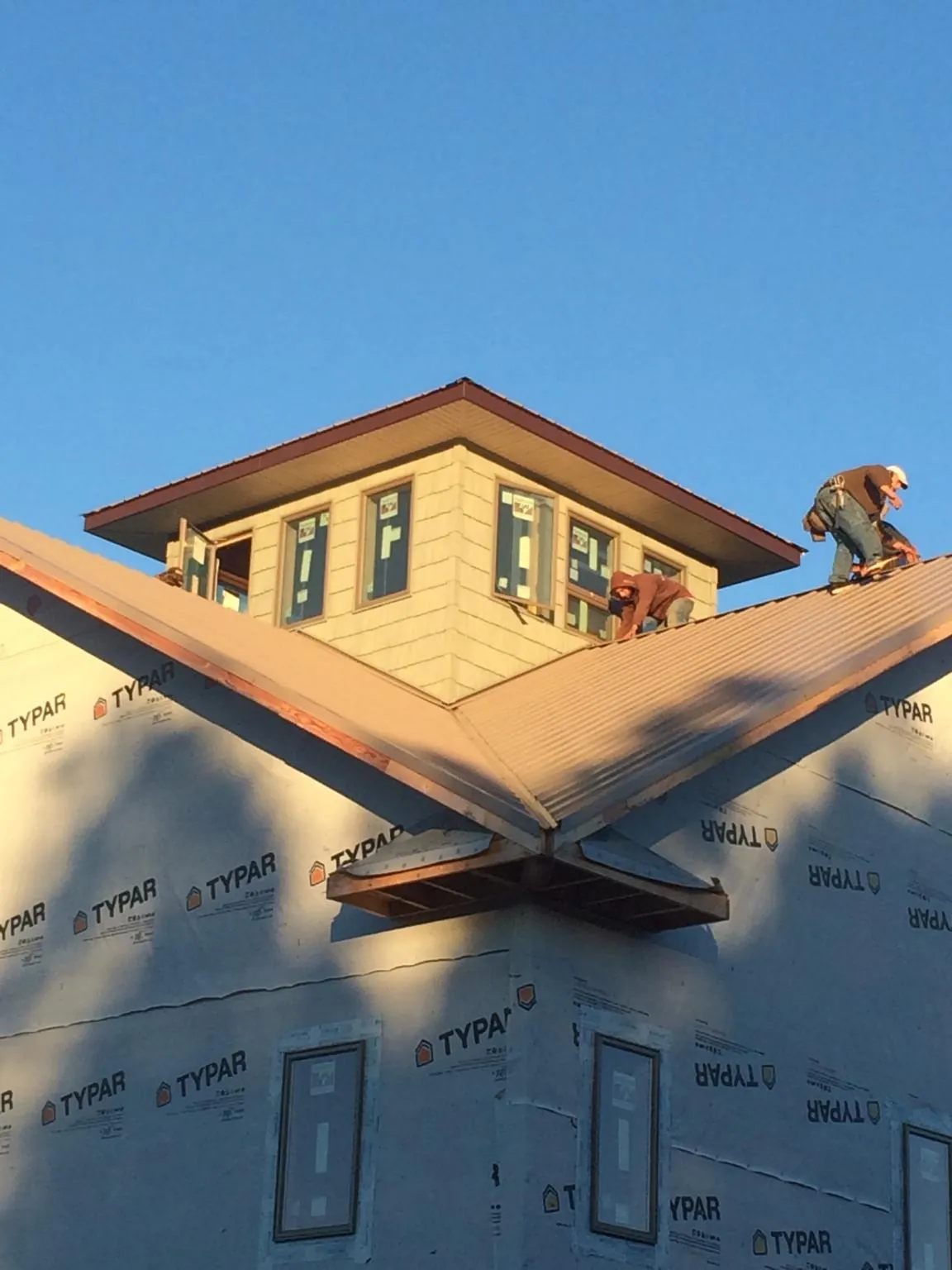Roofers working around a rooftop cupola on a new metal roof at sunset — Roof Waterproofing in Crownsville by Roofing Brothers